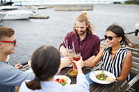 Two couples enjoy drinks and a meal at a dock and dine restaurant near homes for sale in Lavallette