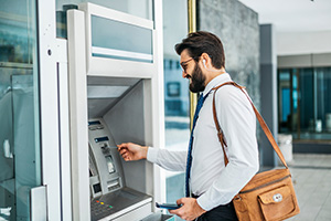 Customer smiling while using a through-the-wall ATM provided by NCR dealers in NJ